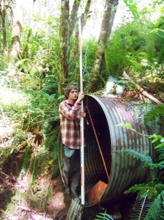 Fish passage barrier assessment intern measuring a culvert.